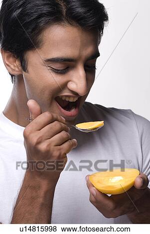 A man eating a mango View Large Photo Image Stock Photo - A man eating a mango. Fotosearch