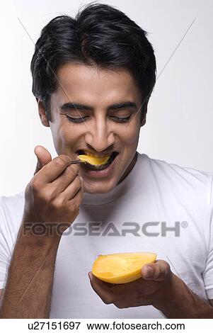 Stock Photo - A man eating a mango. Fotosearch