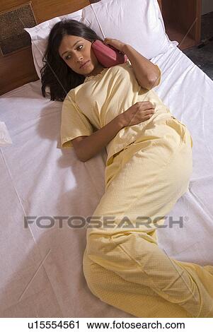 Stock Image - A woman applying a hot water bag. Fotosearch