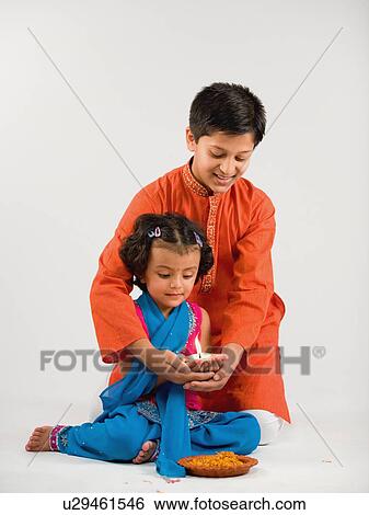 Boy and girl holding a diya together View Large Photo Image Stock Photograph - Boy and girl holding a diya together. Fotosearch