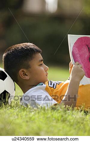Boy lying with football under his head View Large Photo Image Stock Photo - Boy lying with football under his head. Fotosearch