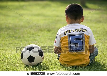 Boy sitting with a football on his side View Large Photo Image Stock Photography - Boy sitting with a football on his side. Fotosearch