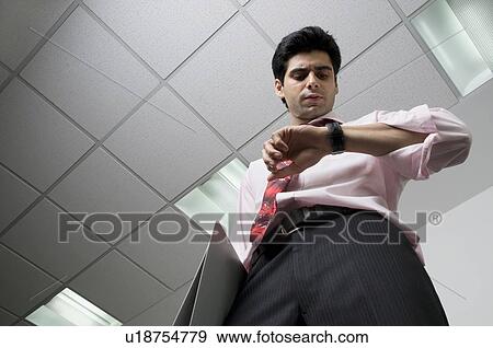 Stock Photo - Business executive looking at his watch. Fotosearch