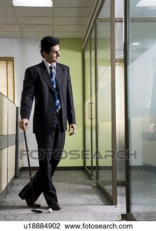 Stock Image - Business executive with golf club. Fotosearch