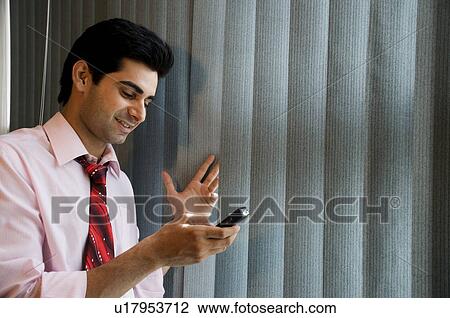 Stock Image - Business executive with his cell phone. Fotosearch