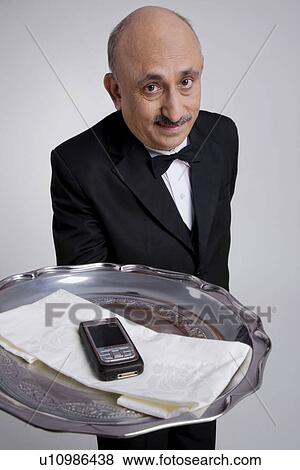 Butler serving a mobile phone View Large Photo Image Stock Photo - Butler serving a mobile phone. Fotosearch