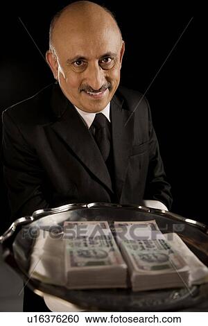 Stock Image - Butler serving money on a tray. Fotosearch