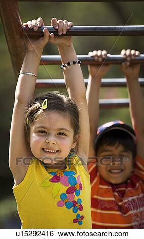 Stock Photograph - Children hanging on monkey bars. Fotosearch