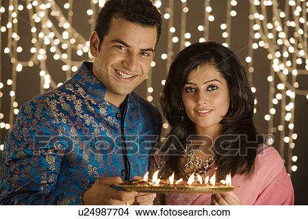 Picture - Couple holding a tray of diyas. Fotosearch