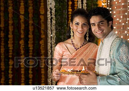 Stock Photo - Couple holding a tray of diyas. Fotosearch