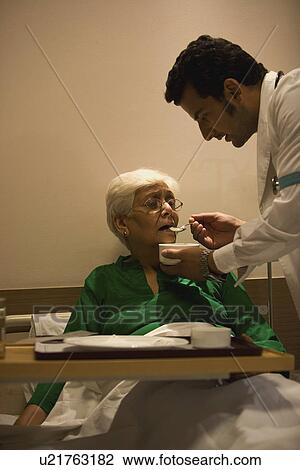 Stock Image - Doctor feeding his patient. Fotosearch
