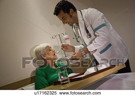 Stock Photography - Doctor feeding his patient. Fotosearch
