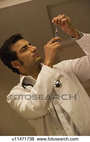 Stock Photo - Doctor filling up a syringe. Fotosearch