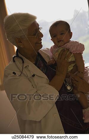 Doctor holding a baby View Large Photo Image Stock Photo - Doctor holding a baby. Fotosearch