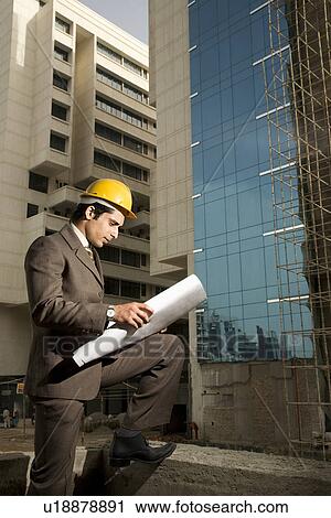Stock Image - Engineer looking at blueprints. Fotosearch