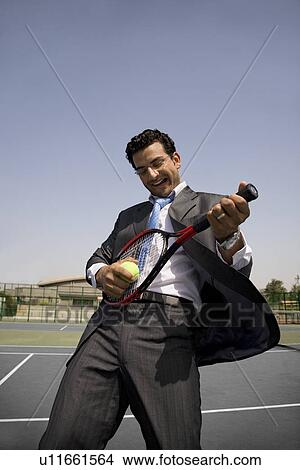 Picture - Executive holding a racket and a ball. Fotosearch