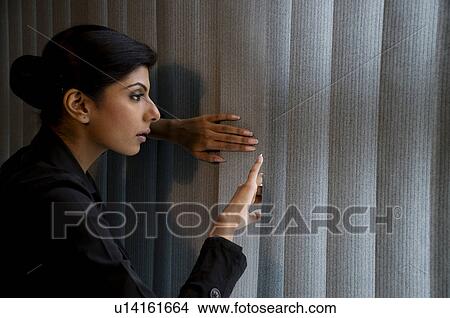 Picture - Executive peeking out the window. Fotosearch