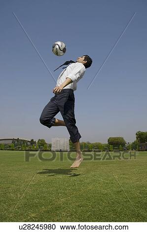 Stock Image - Executive playing with a football. Fotosearch