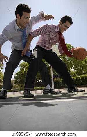 Stock Image - Executives playing basketball. Fotosearch