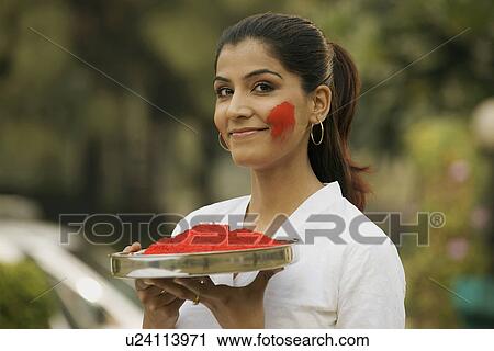 Stock Image - Girl holding a plate of gulal. Fotosearch