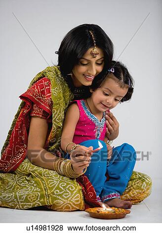 Stock Photo - Girl lighting diya. Fotosearch