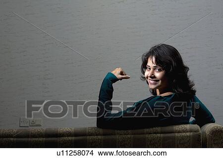 Picture - Girl sitting on a couch. Fotosearch