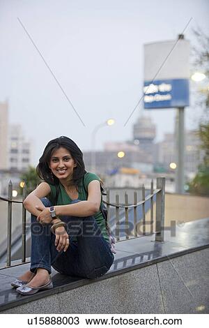 Stock Image - Girl sitting on a wall. Fotosearch