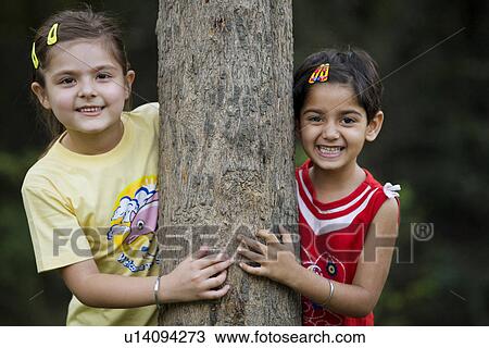 Girls behind a tree View Large Photo Image Stock Image - Girls behind a tree. Fotosearch