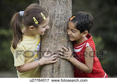 Stock Photo - Girls hugging a tree. Fotosearch
