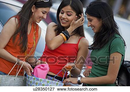 Stock Photo - Girls looking into their shopping bags. Fotosearch