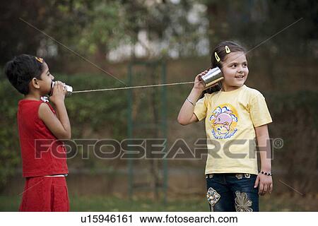 Stock Image - Girls talking through tin can phone. Fotosearch