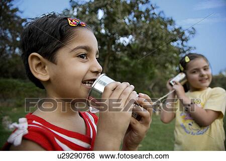 Girls talking through tin can phone View Large Photo Image Stock Photo - Girls talking through tin can phone. Fotosearch