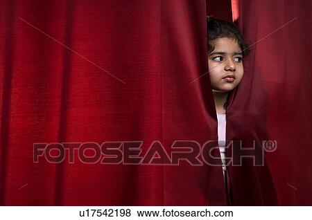 Stock Photo - Little girl peeking out from the curtain. Fotosearch