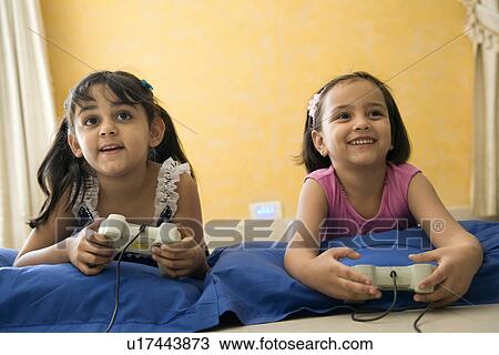 Stock Image - Little girls playing video game. Fotosearch