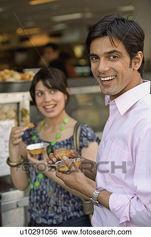 Stock Photograph - Man and woman having street food. Fotosearch