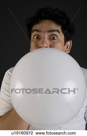 Stock Image - Man blowing air into a balloon. Fotosearch