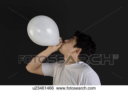 Stock Photograph - Man blowing air into a balloon. Fotosearch