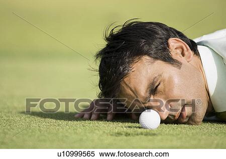 Stock Photography - Man looking at golf ball. Fotosearch
