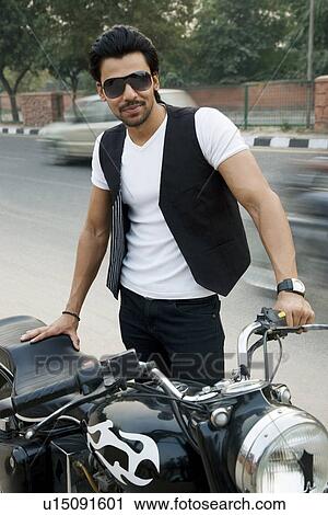 Stock Image - Man posing with his motorcycle. Fotosearch
