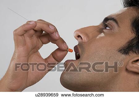Man putting a pill in his mouth View Large Photo Image Stock Photo - Man putting a pill in his mouth. Fotosearch