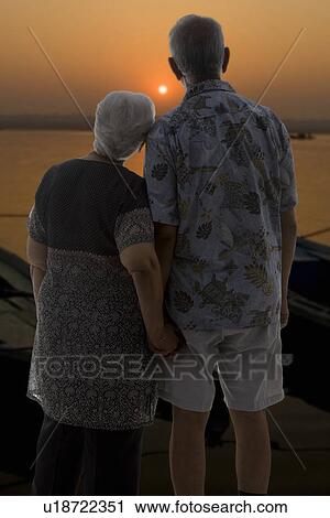 Stock Image - Old couple enjoying the sunset. Fotosearch