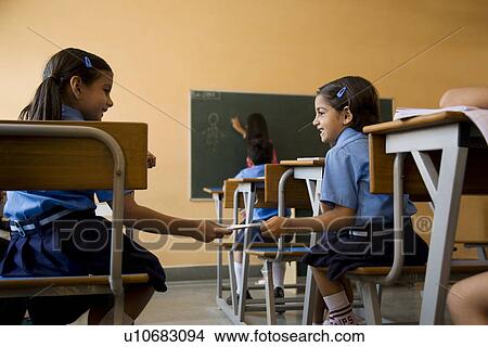 Picture - School girls exchanging a notebook. Fotosearch