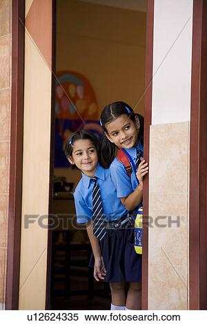Stock Photography - School girls peeking from a classroom. Fotosearch