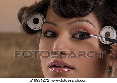Stock Image - Woman applying makeup on her face. Fotosearch
