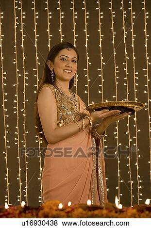 Stock Photo - Woman holding a tray of diyas. Fotosearch