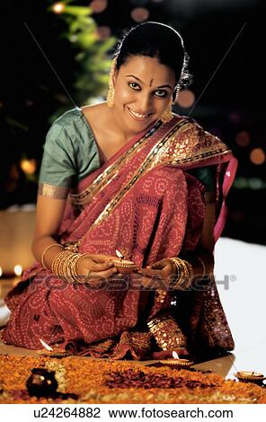 Woman lighting diyas on Diwali evening View Large Photo Image Stock Image - Woman lighting diyas on Diwali evening. Fotosearch