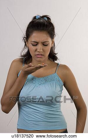 Stock Image - Woman looking at pills. Fotosearch