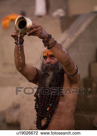 Stock Image - Bearded man in India pouring water out of a container. Fotosearch