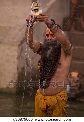 Stock Image - Bearded man in India pouring water out of a container. Fotosearch