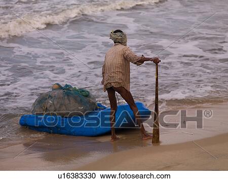 Stock Image - Fisherman on the beach of Arabian Sea. Fotosearch